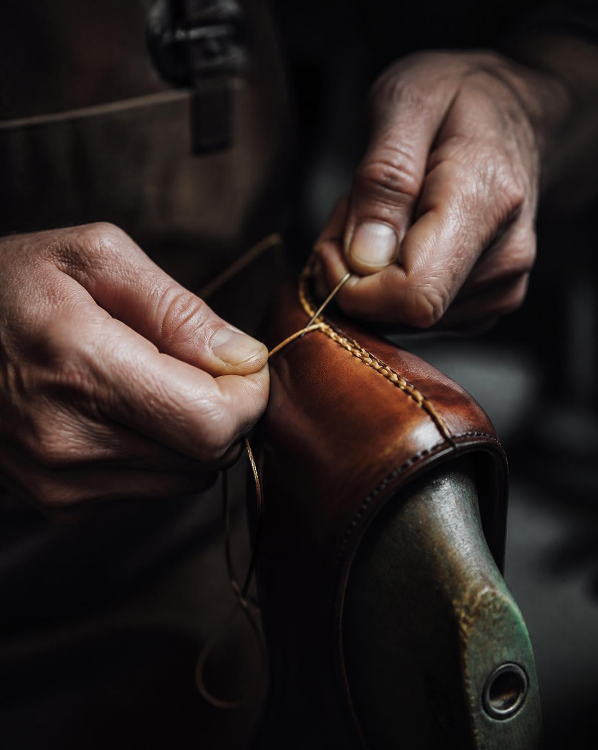 Artisan hand-stitching a leather shoe upper on a last